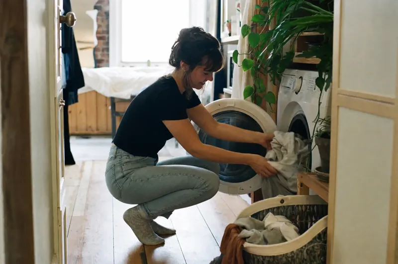 Une femme met du linge dans sa laveuse neuve